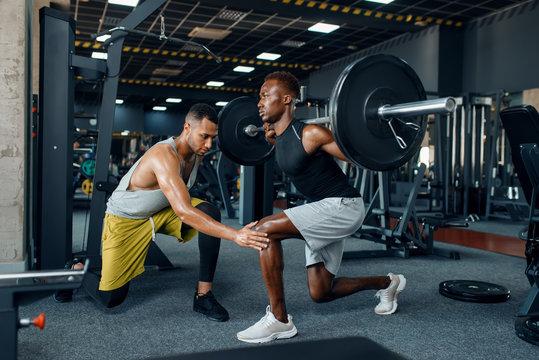 Personal trainer coaching a squat in a gym